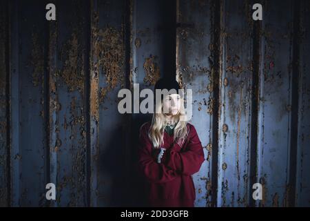 Portrait d'une adolescente blonde debout à l'intérieur dans un bâtiment abandonné. Banque D'Images