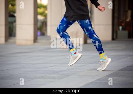 Jambes de femme en gros plan avec des leggins bleu vif et des chaussettes jaunes en plein air. Banque D'Images