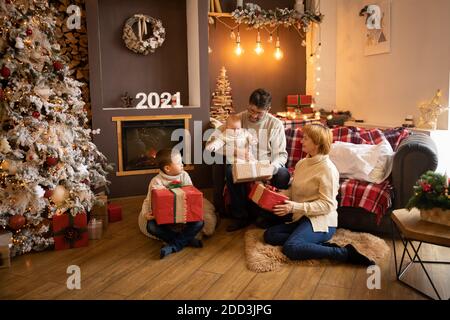 Ouverture de la famille cadeaux de Noël près de l'arbre de Noël dans la maison décorée, bonne année 2021 Banque D'Images