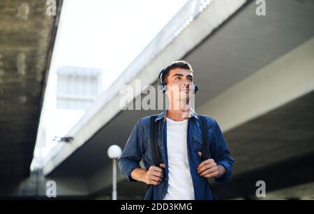 Vue en contre-angle d'un jeune homme attrayant avec un casque en plein air en ville. Banque D'Images