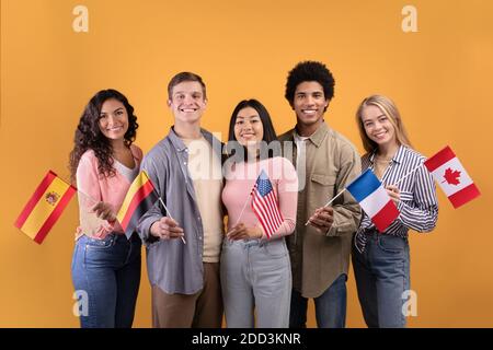 Étudiant multiethnique de Smilinge dans une ambiance décontractée, tenez de petits drapeaux Banque D'Images
