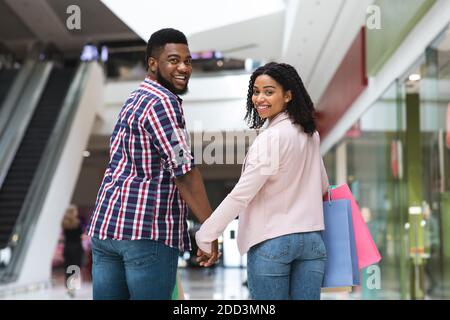 Loisirs pour couple. Black Man and Woman marchant dans le centre commercial, en tenant les mains Banque D'Images