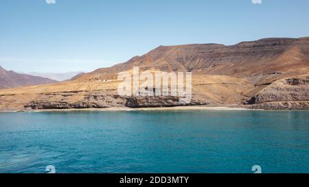 Approche de l'île de Fuerteventura à son point le plus méridional, à Morro Jable avec l'affichage de l'isolement des falaises et des montagnes arides derrière Banque D'Images