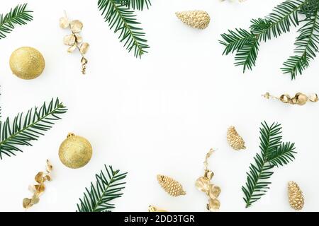 Cadre de Noël avec branches d'arbre à feuilles persistantes et décoration dorée sur fond blanc. Flat lay, vue de dessus Banque D'Images