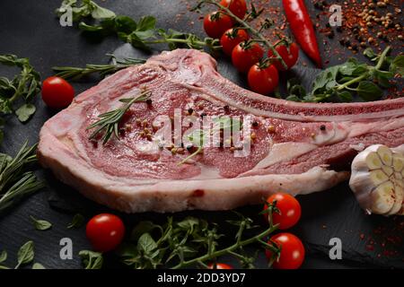 Steak de bœuf cru frais sur le tableau noir avec herbes et épices Banque D'Images