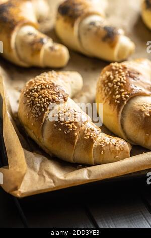 Petit pain croissant salé sur un papier de cuisson. Pâtisserie maison. Banque D'Images