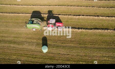 Fabrication de foin : herbe coupée collectée. Tracteur et presse à foin dans un champ, ferme à Guipel (Bretagne, nord-ouest de la France) Banque D'Images