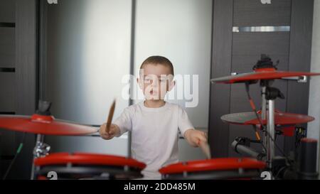 Un jeune garçon en tant que batteur talentueux d'un groupe de rock. Un adolescent américain beau et cool joue un kit de batterie à la maison. Batteur garçon pratiquant le batteur à Banque D'Images