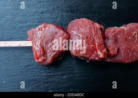 Brochettes de kebab frais et cru ou de viande de shashlik au barbecue.steaks de viande de bœuf cru et frais sur fond noir. Banque D'Images