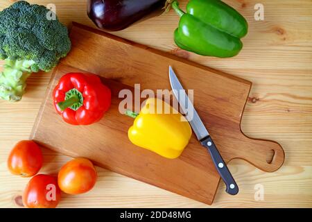 Vue de dessus du poivron jaune sur la planche à découper avec Couteau et autres légumes dispersés Banque D'Images