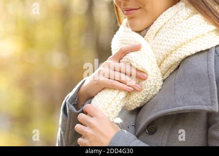 Gros plan des mains de la femme mettant un foulard dans un parc en hiver Banque D'Images