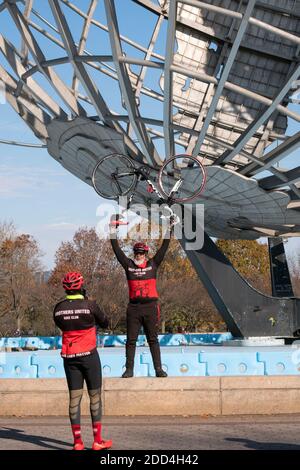 Un membre du Brothers United Bicycle Club pose pour une photo tenant son vélo au-dessus de la tête avec le Unisphere en arrière-plan. Banque D'Images