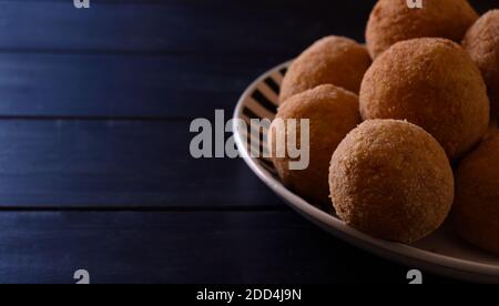 Arancini, cuisine italienne de rue. Boulettes frites, faites de riz, de viande et de légumes sur une assiette et une table bleue. Banque D'Images