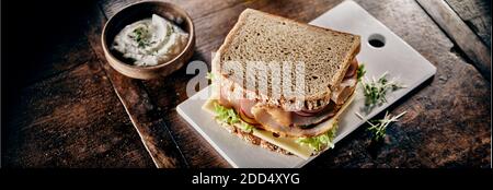 Sandwich au jambon avec, cresson au fromage et salade verte sur du pain brun wholegrain sain servi sur une planche à découper sur une table en bois rustique avec du mayonnaise Banque D'Images