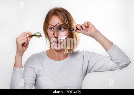 Finance et banque. Une jeune blonde tient une pile de dollars dans ses mains, et les regarde avec surprise à travers une loupe. Fond blanc Banque D'Images