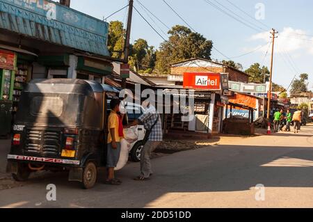 Un homme charge un sac de grains à son pousse-pousse automatique, également connu comme un tuk-tuk, dans le petit village d'Umsning, Meghalaya, Inde. Banque D'Images