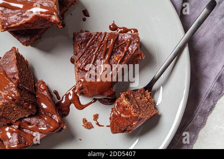 Carrés de brownie vegan avec chocolat noir sur une assiette grise, vue du dessus. Concept de dessert végétalien. Banque D'Images