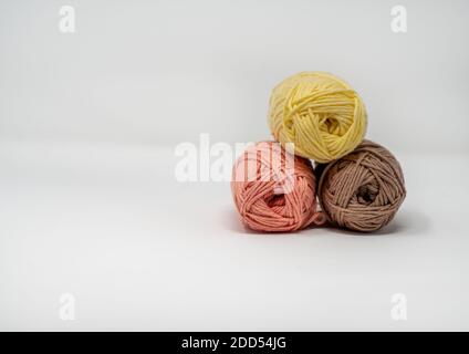 Trois balles de fil de laine coloré sur un fond blanc Uni avec espace de copie. Banque D'Images