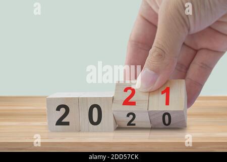 Concept de bonne année. Retournez les cubes en bois 2020 à la main et passez à 2021 sur la table en bois. Banque D'Images