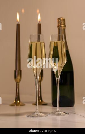 Sélectionnez une sélection de verres à champagne avec deux bougies allumées et une bouteille de champagne à l'arrière. Alcool et célébration de Noël. Banque D'Images