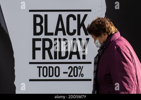 Madrid, Espagne. 24 novembre 2020. Une femme portant un masque facial pour se protéger contre le coronavirus passant par un panneau qui annonce un rabais pour le Black Friday sur la fenêtre d'exposition d'un magasin dans le centre de Madrid. Selon l'étude iAhorro sur les intentions d'achat, les Espagnols dépenseront 10% de moins pour ce Vendredi fou en raison de la pandémie de COVID-19. Credit: Marcos del Mazo/Alay Live News Banque D'Images