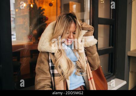 Belle fille blonde une sensation de froid, essayant de se protéger contre le gel en ville le jour de l'hiver. Young caucasian woman en attente d'ami sur le s Banque D'Images