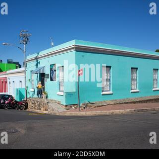 Bo-Kaap, le Cap- 10/11/2020 immeuble d'art bleu à Bo-Kaap. Femme portant du jaune à l'entrée du bâtiment. Banque D'Images