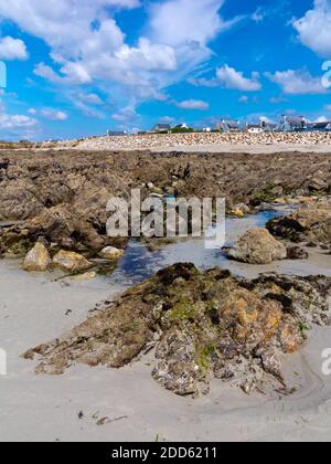 Marée basse sur la plage de la Plage de Penhors, Pouldreuzic, Finistère au nord-ouest de la Bretagne, France avec des maisons visibles au loin. Banque D'Images