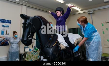 East Lothian, Écosse, Royaume-Uni, NHS Lothian & Muirfield Riding Therapy célèbre 10 ans d'hippothérapie : la physiothérapeute Heather Falconer a été la première à proposer le Children's Therapeutic Riding Service (service d'équitation thérapeutique pour les enfants) en offrant gratuitement de l'équitation thérapeutique aux enfants, aux jeunes et aux adultes handicapés. Le service a été le premier en Écosse pour les enfants ayant des problèmes de mobilité, d'équilibre, de tonus musculaire et de coordination. Oreo, un cheval mécanique, permet aux jeunes d'avoir de la physiothérapie amusante. Kyle Clark, âgé de 8 ans, fait le tour du simulateur de cheval mécanique de Racewood Banque D'Images