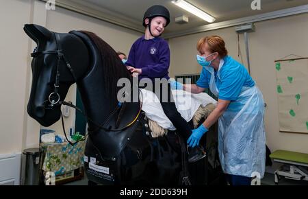 East Lothian, Écosse, Royaume-Uni, NHS Lothian & Muirfield Riding Therapy célèbre 10 ans d'hippothérapie : la physiothérapeute Heather Falconer a été la première à proposer le Children's Therapeutic Riding Service (service d'équitation thérapeutique pour les enfants) en offrant gratuitement de l'équitation thérapeutique aux enfants, aux jeunes et aux adultes handicapés. Le service a été le premier en Écosse pour les enfants ayant des problèmes de mobilité, d'équilibre, de tonus musculaire et de coordination. Oreo, un cheval mécanique, permet aux jeunes d'avoir de la physiothérapie amusante. Kyle Clark, âgé de 8 ans, fait le tour du simulateur de cheval mécanique de Racewood Banque D'Images