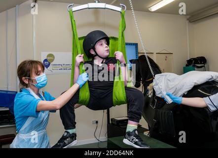 East Lothian, Écosse, Royaume-Uni, NHS Lothian & Muirfield Riding Therapy célèbre 10 ans d'hippothérapie : la physiothérapeute Heather Falconer a été la première à proposer le Children's Therapeutic Riding Service (service d'équitation thérapeutique pour les enfants) en offrant gratuitement de l'équitation thérapeutique aux enfants, aux jeunes et aux adultes handicapés. Le service a été le premier en Écosse pour les enfants ayant des problèmes de mobilité, d'équilibre, de tonus musculaire et de coordination. Oreo, un cheval mécanique, permet aux jeunes d'avoir de la physiothérapie amusante. Louis Macdiarmid, âgé de 10 ans, est hissé sur le simulateur de cheval mécanique de Racewood Banque D'Images