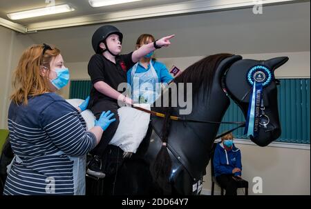 East Lothian, Écosse, Royaume-Uni, NHS Lothian & Muirfield Riding Therapy célèbre 10 ans d'hippothérapie : la physiothérapeute Heather Falconer a été la première à proposer le Children's Therapeutic Riding Service (service d'équitation thérapeutique pour les enfants) en offrant gratuitement de l'équitation thérapeutique aux enfants, aux jeunes et aux adultes handicapés. Le service a été le premier en Écosse pour les enfants ayant des problèmes de mobilité, d'équilibre, de tonus musculaire et de coordination. Oreo, un cheval mécanique, permet aux jeunes d'avoir de la physiothérapie amusante. Louis Macdiarmid, âgé de 10 ans, fait le tour du simulateur de cheval mécanique de Racewood Banque D'Images