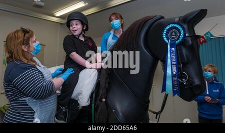 East Lothian, Écosse, Royaume-Uni, NHS Lothian & Muirfield Riding Therapy célèbre 10 ans d'hippothérapie : la physiothérapeute Heather Falconer a été la première à proposer le Children's Therapeutic Riding Service (service d'équitation thérapeutique pour les enfants) en offrant gratuitement de l'équitation thérapeutique aux enfants, aux jeunes et aux adultes handicapés. Le service a été le premier en Écosse pour les enfants ayant des problèmes de mobilité, d'équilibre, de tonus musculaire et de coordination. Oreo, un cheval mécanique, permet aux jeunes d'avoir de la physiothérapie amusante. Louis Macdiarmid, âgé de 10 ans, pilote un simulateur de cheval mécanique de Racewood Banque D'Images