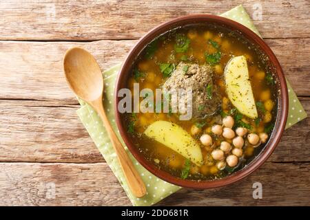 Soupe Kufta bozbash faite de boules de viande d'agneau, pois chiches, pommes de terre et herbes dans une assiette sur la table. Vue horizontale du dessus Banque D'Images
