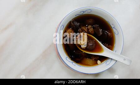 Soupe de champignons blancs chinois et de palangane, dans un bol avec une cuillère à soupe chinoise, placé sur une table en marbre. Vue de dessus. Banque D'Images