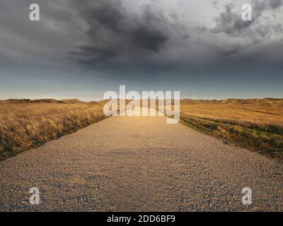 Route de gravier vide menant à un orage. Banque D'Images