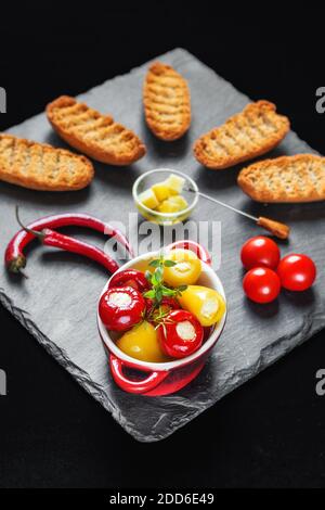 Petits poivrons rouges et jaunes fourrés de fromage (délicatesse balkanique) servis avec des rusk, des piments et des tomates cerises (attention sélective) Banque D'Images