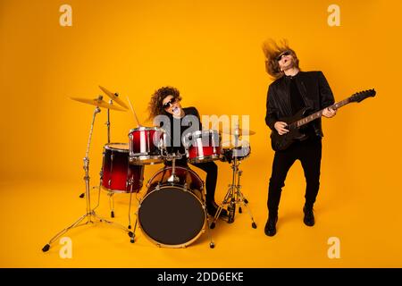 Spectacle en direct de groupe de punk populaire. Photo pleine grandeur de deux personnes ont nuit club événement festival tour homme jouer guitare fille tambour Drumstick Banque D'Images