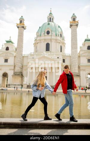 Joyeux jeune couple marchant près de l'église catholique Saint-Pierre à Vienne, en Autriche Banque D'Images