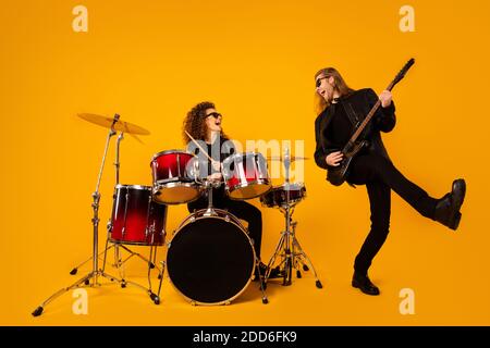 Photo pleine grandeur de deux personnes célèbre punk artiste homme jouer guitare basse fille tambour profiter de l'enregistrement d'un nouveau spectacle de composition portez des bottes de veste sans mousse isolées Banque D'Images