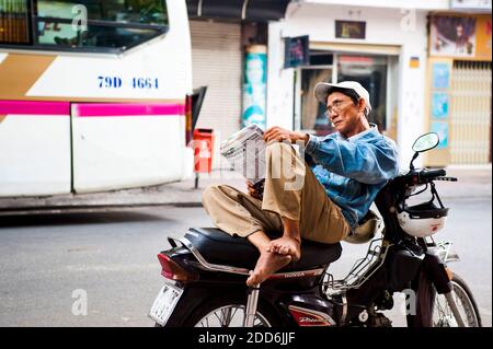 Homme lisant le journal sur son Mooped dans une scène de rue typique à Ho Chi Minh ville, Vietnam, Asie du Sud-est Banque D'Images