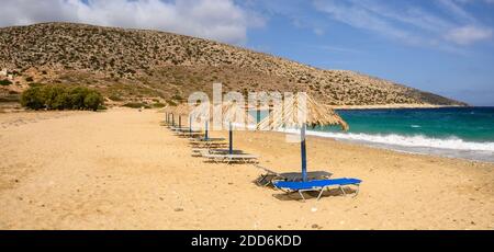 Chaises longues et parasols à la plage d'Agia Theodoti sur l'île d'iOS. Une plage merveilleuse avec le sable doré et les eaux azur. Cyclades, Grèce Banque D'Images