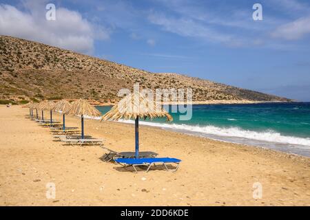 Chaises longues et parasols à la plage d'Agia Theodoti sur l'île d'iOS. Une plage merveilleuse avec le sable doré et les eaux azur. Cyclades, Grèce Banque D'Images