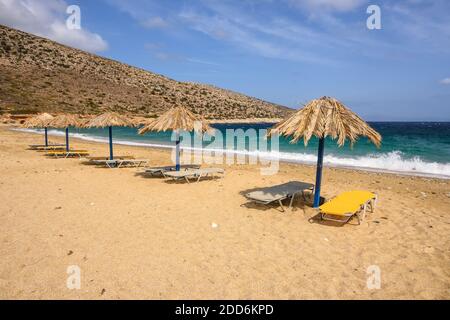 Chaises longues et parasols à la plage d'Agia Theodoti sur l'île d'iOS. Une plage merveilleuse avec le sable doré et les eaux azur. Cyclades, Grèce Banque D'Images