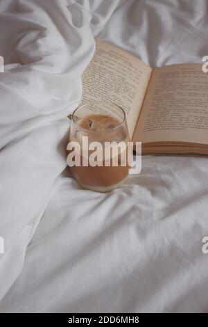 Fermez le café glacé avec des glaçons. Feuille blanche accompagnée d'un livre ouvert. Détails esthétiques minimalistes. Photographie de produit 2020. Banque D'Images