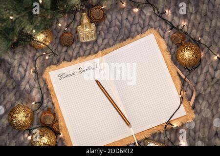 Bloc-notes avec l'inscription cher père noël sur fond gris tricoté avec décorations de noël, plat Banque D'Images