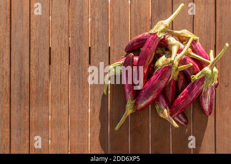 Vue d'en haut sur un groupe d'aubergines. Les aubergines sont situées sur le côté droit d'une surface en bois. La lumière du soleil se reflète sur la nourriture. Banque D'Images