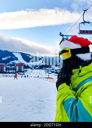 joyeux homme en tenue de ski avec chapeau de noël rouge père noël en hiver, les montagnes de la colline de l'espace de copie Banque D'Images