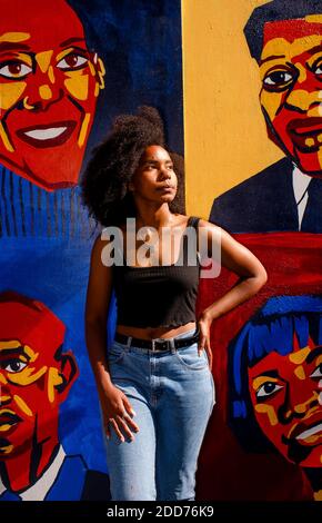 Belle artiste en lumière dorée affiche sa murale de Noir héros Banque D'Images