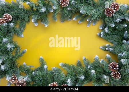 La guirlande d'arbres de Noël entoure l'espace pour l'inscription sur un fond jaune. Copier l'espace Banque D'Images